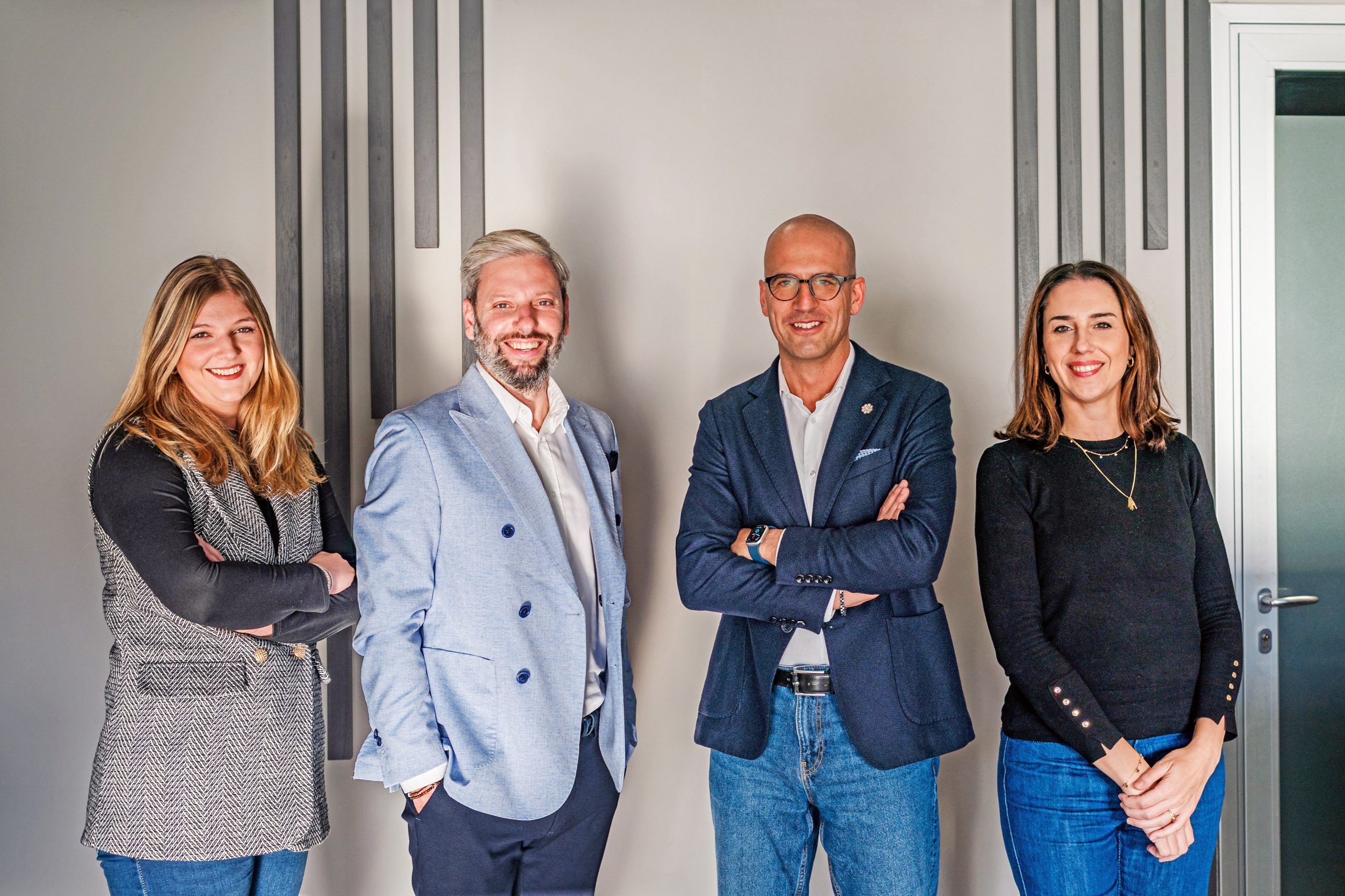 Foto di 4 persone in piedi in posa su sfondo grigio